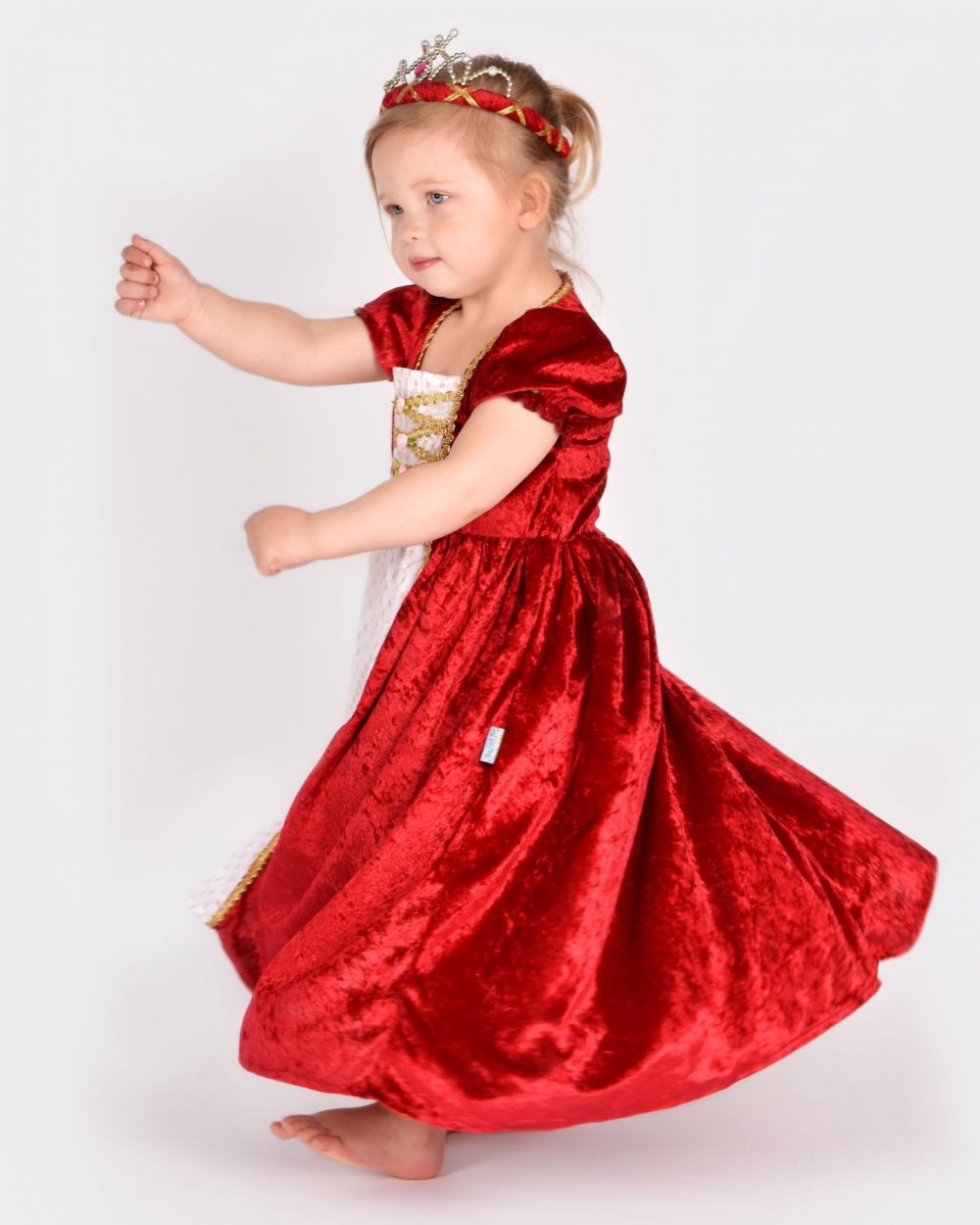 Flicka snurrar runt iklädd en röd prinsessklänning och röd tiara.