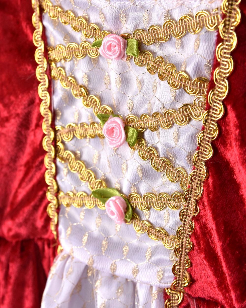 Närbild på en röd prinsessklänning. I bild visas bröstpartiet på klänningen som har en vitt sidenparti, gyllene detaljer och små rosdekorationer i rosa.