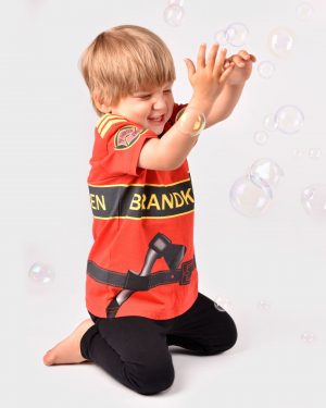 skrattande barn iklädd röd brandmanst-shirt leker med såpbubblor