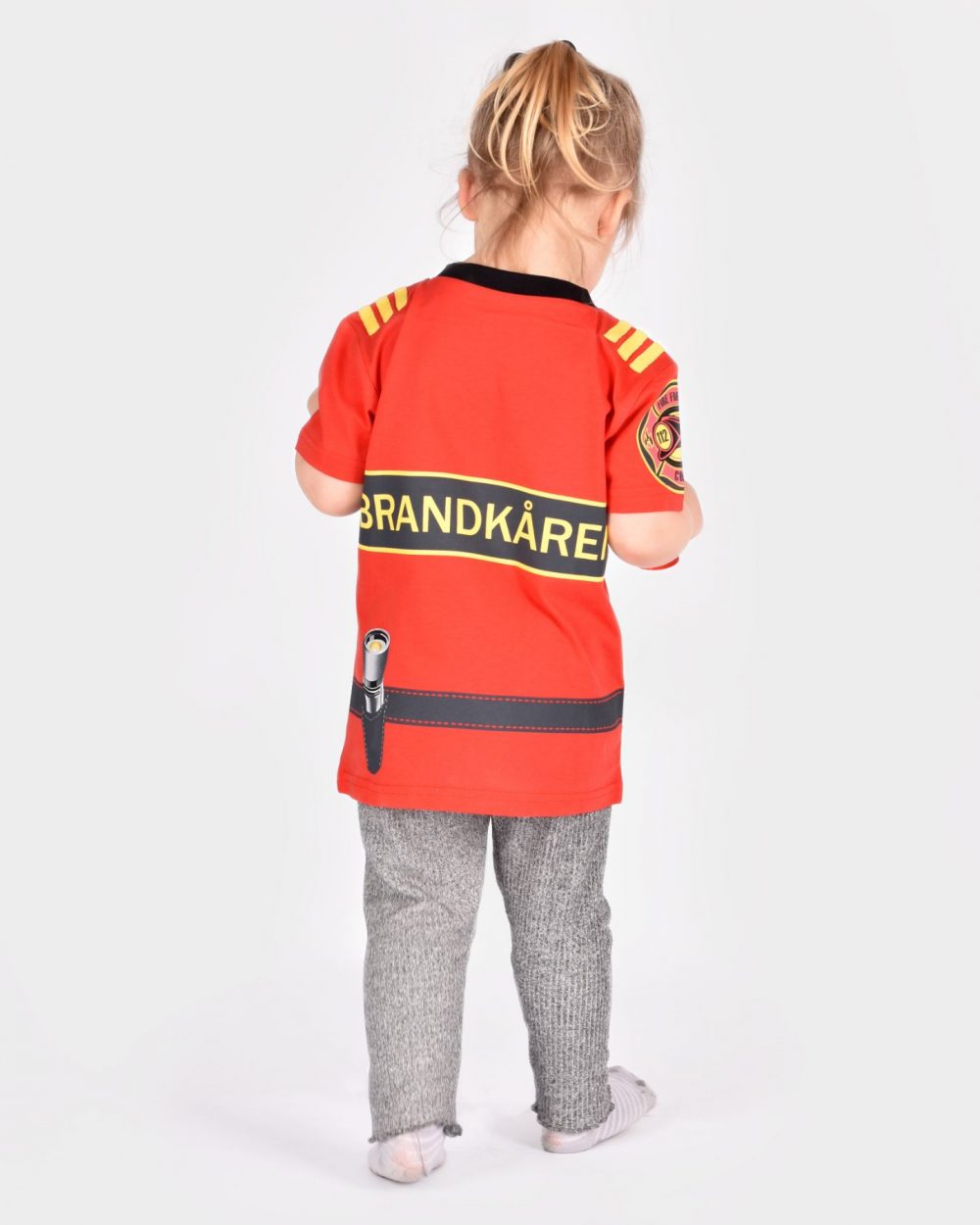 barn iklädd röd brandmanst-shirt visas bakifrån