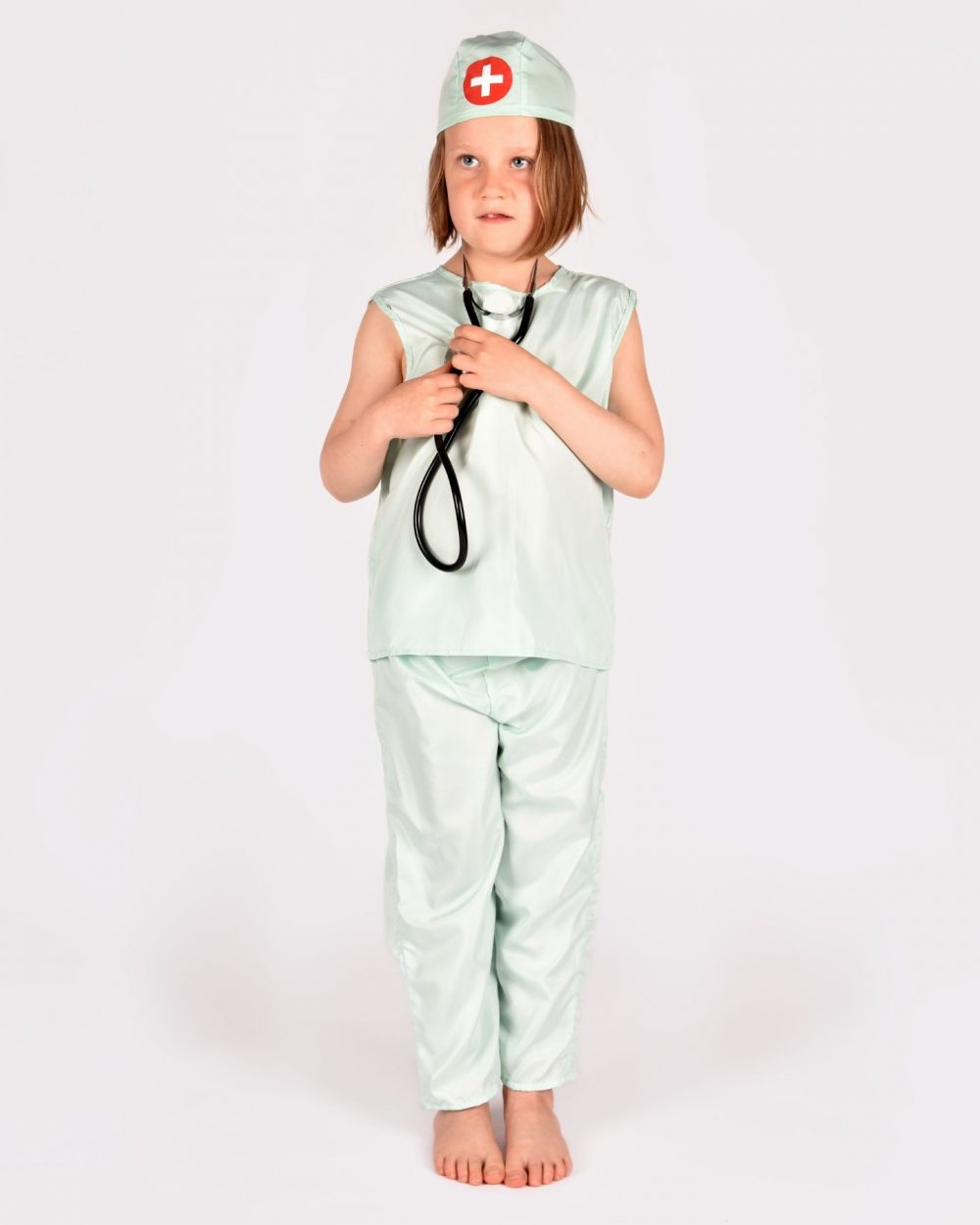 Flicka som bär en mintgrön doktorsdräkt och lyssnar på sitt hjärta med ett svart stetoskop.