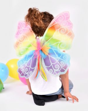 flicka som bär regnbågsfärgade vingar med glitterdetaljer visas bakifrån
