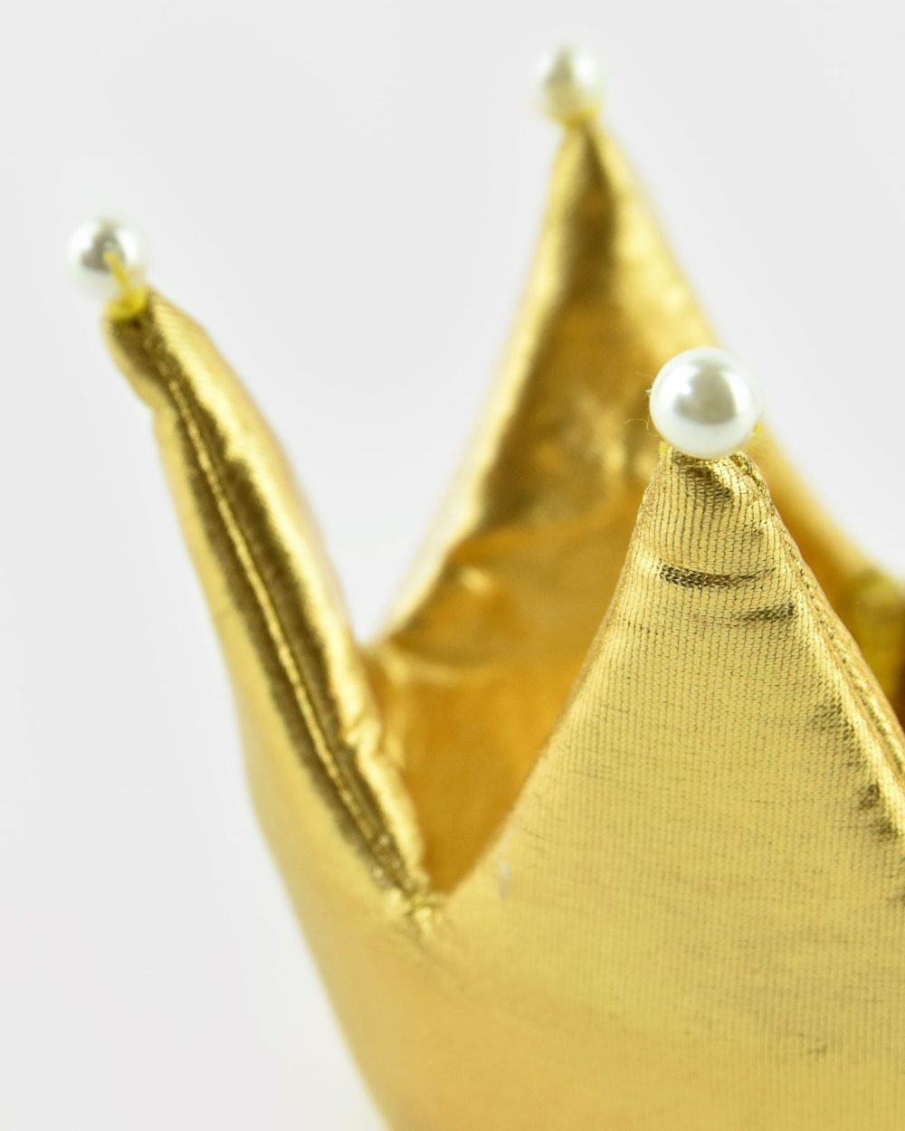 Närbild på en guldig vadderad prinsesskrona med pärldetaljer.