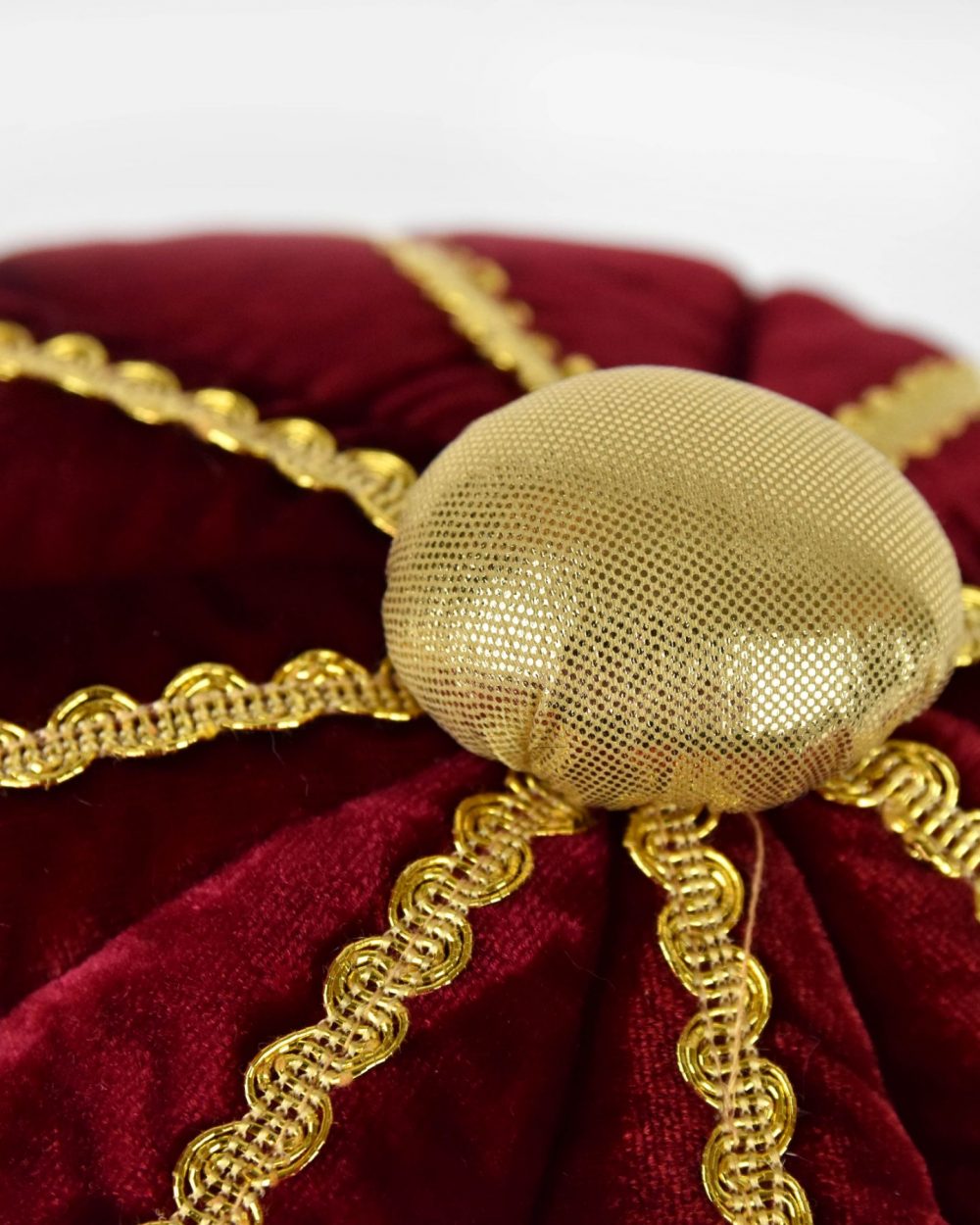 Närbild på kungakrona som visar den guldiga toppknoppen samt ovansidan av kronan som är i röd sammet med gulddetaljer.