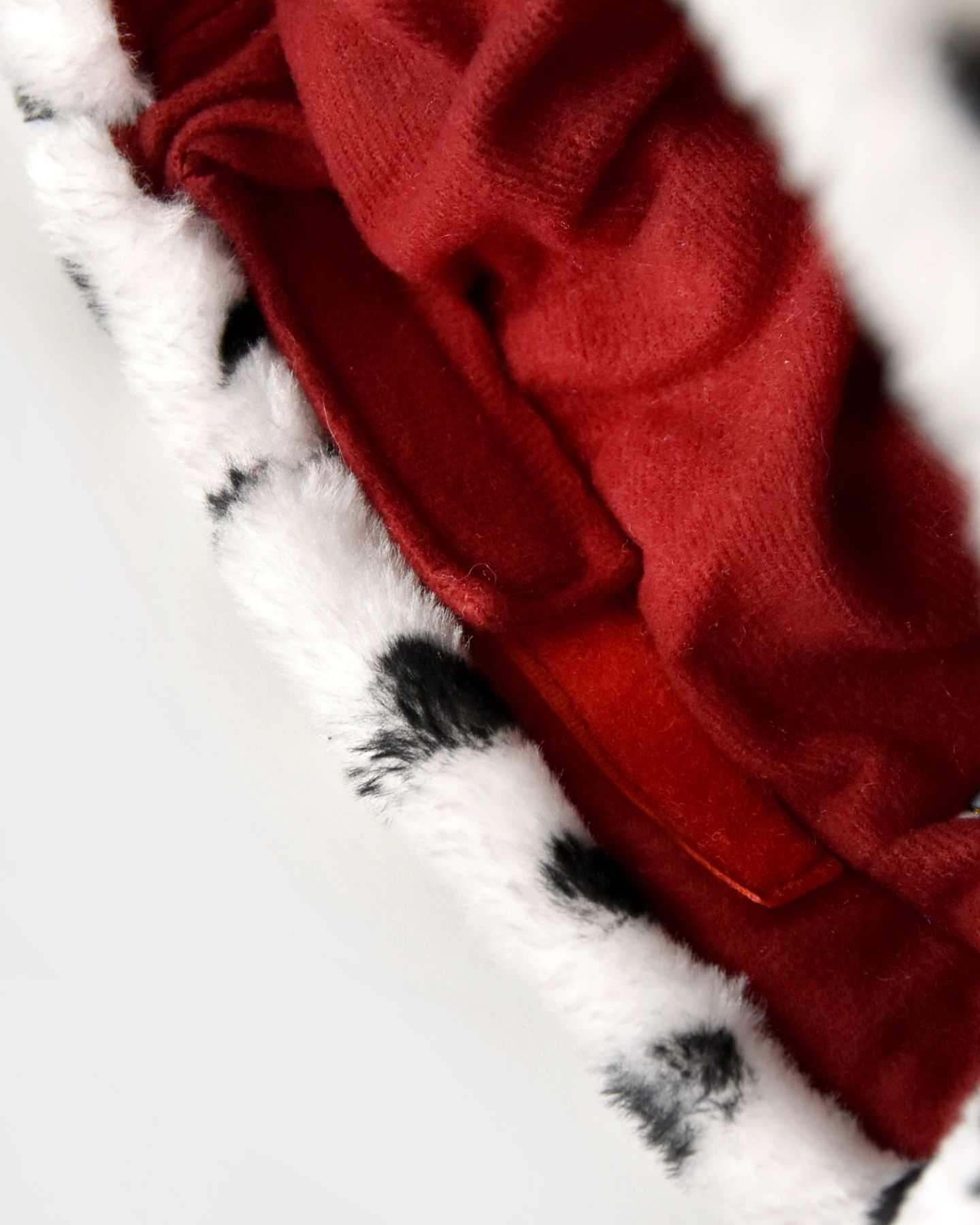 Närbild på kardborrefäste i en kungakrona. I bild syns också en vitsvart fuskpäls och det röda foder som är i kronan.