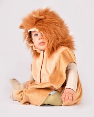 Sittande barn som bär en ljusbrun lejondräkt med huva täckt med en fuskpälsman. På huvan finns också två öron.