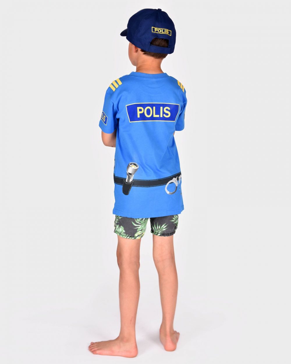 pojke som bär en blå poliskeps och blå polist-shirt visas bakifrån