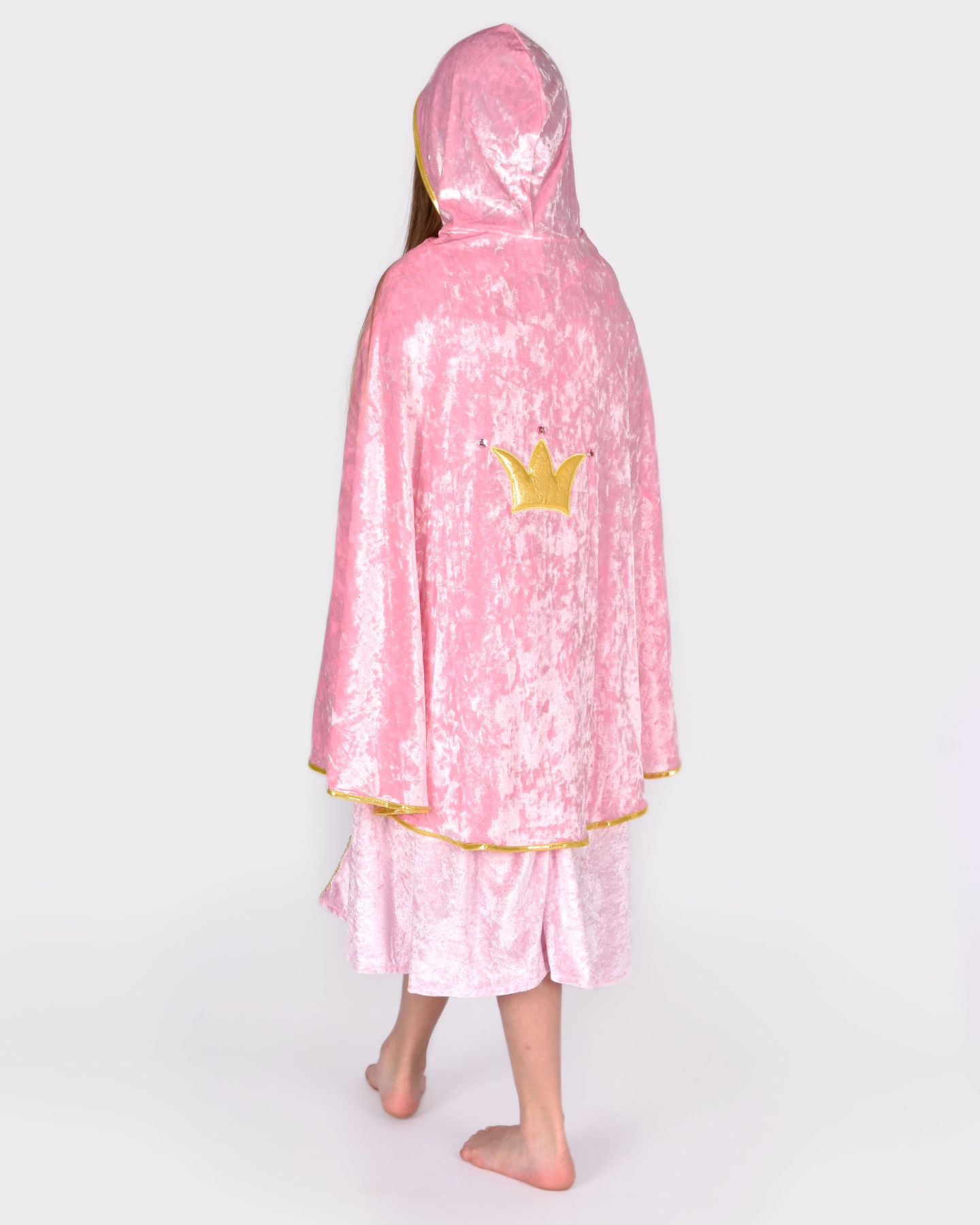 Flicka som bär en prinsesscape i rosa krossad sammet med gulddetaljer visas bakifrån. På capens rygg syns en guldig krona. Capen har en huva.