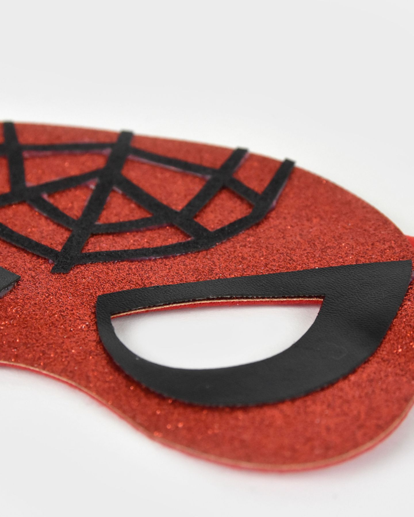 Närbild på en röd glittrig spindelmannenmask med svarta detaljer.