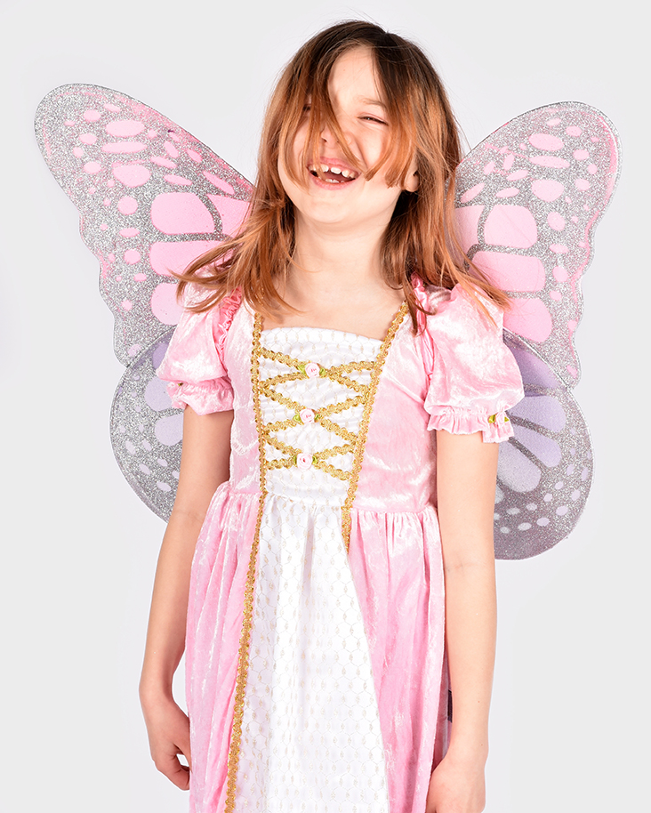 skrattande flicka som bär rosalila fevingar och en rosa prinsessklänning