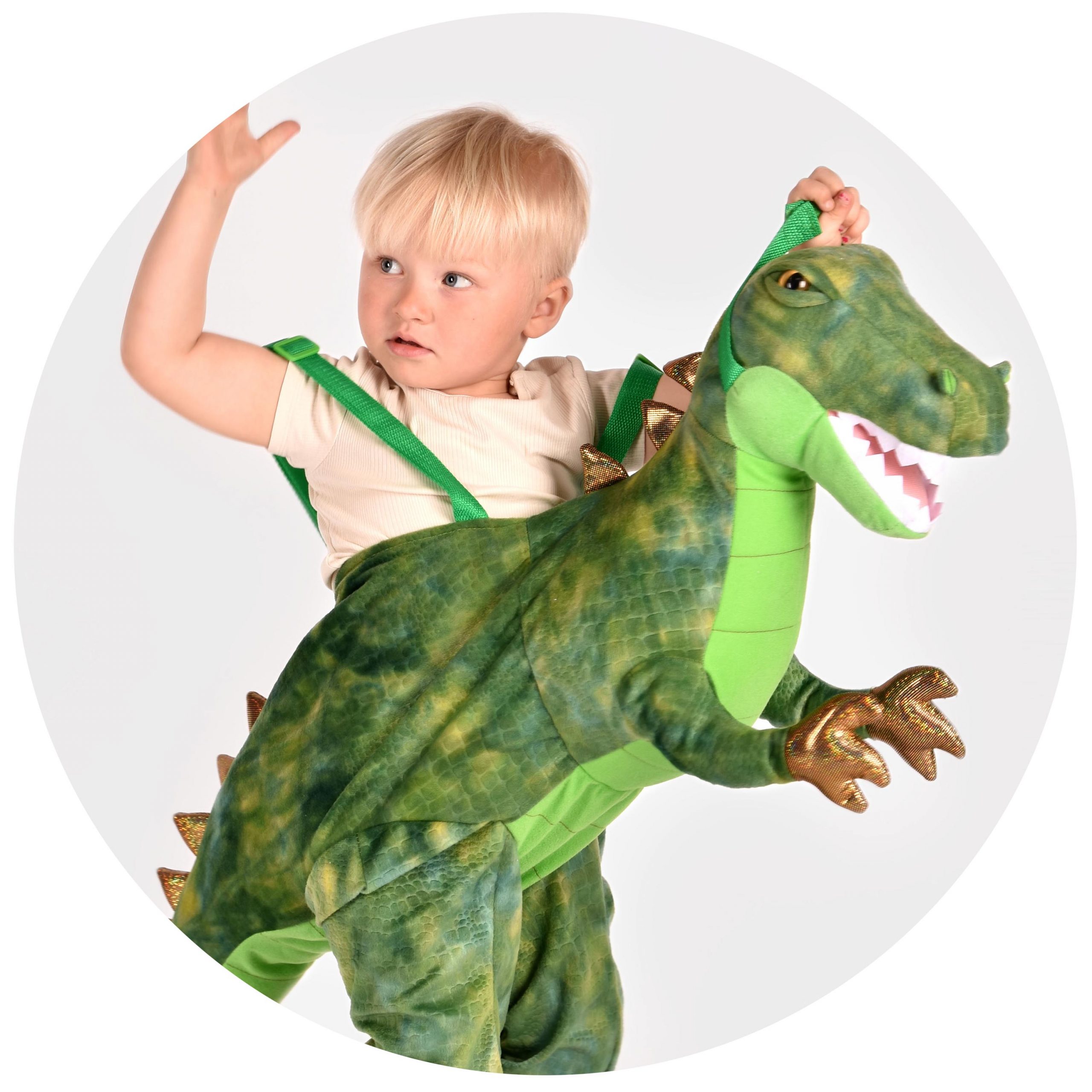 pojke som bär en grön ride-on föreställandes en dinosaurie t-rex
