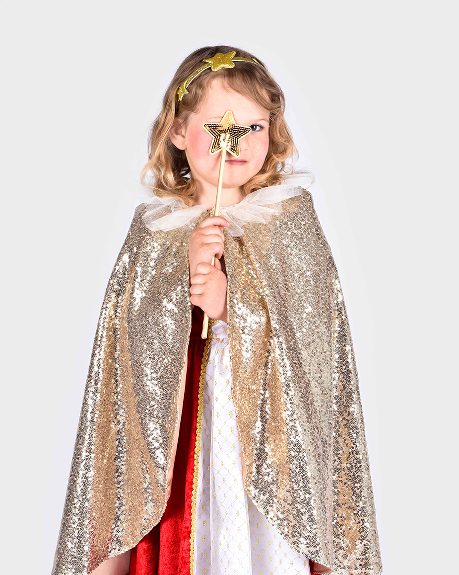 flicka som bär paljettprydd guldig cape, guldglittrigt hårband med stjärndekorationer och trollstav med paljettprydd stjärna på toppen