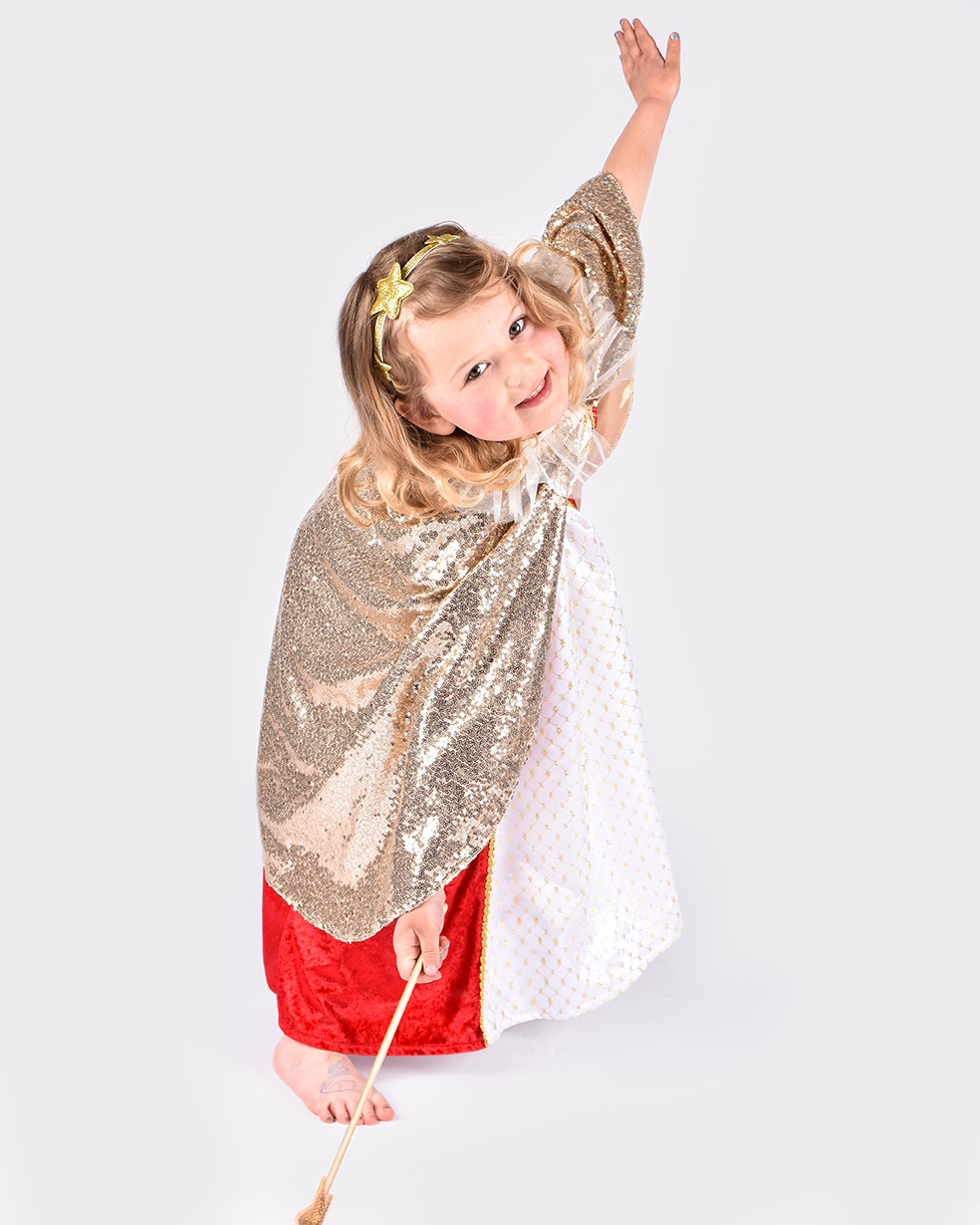 flicka som bär guldig paljettprydd cape, guldglittrigt hårband med stjärndekorationer samt guldig trollstav med stjärna på toppen
